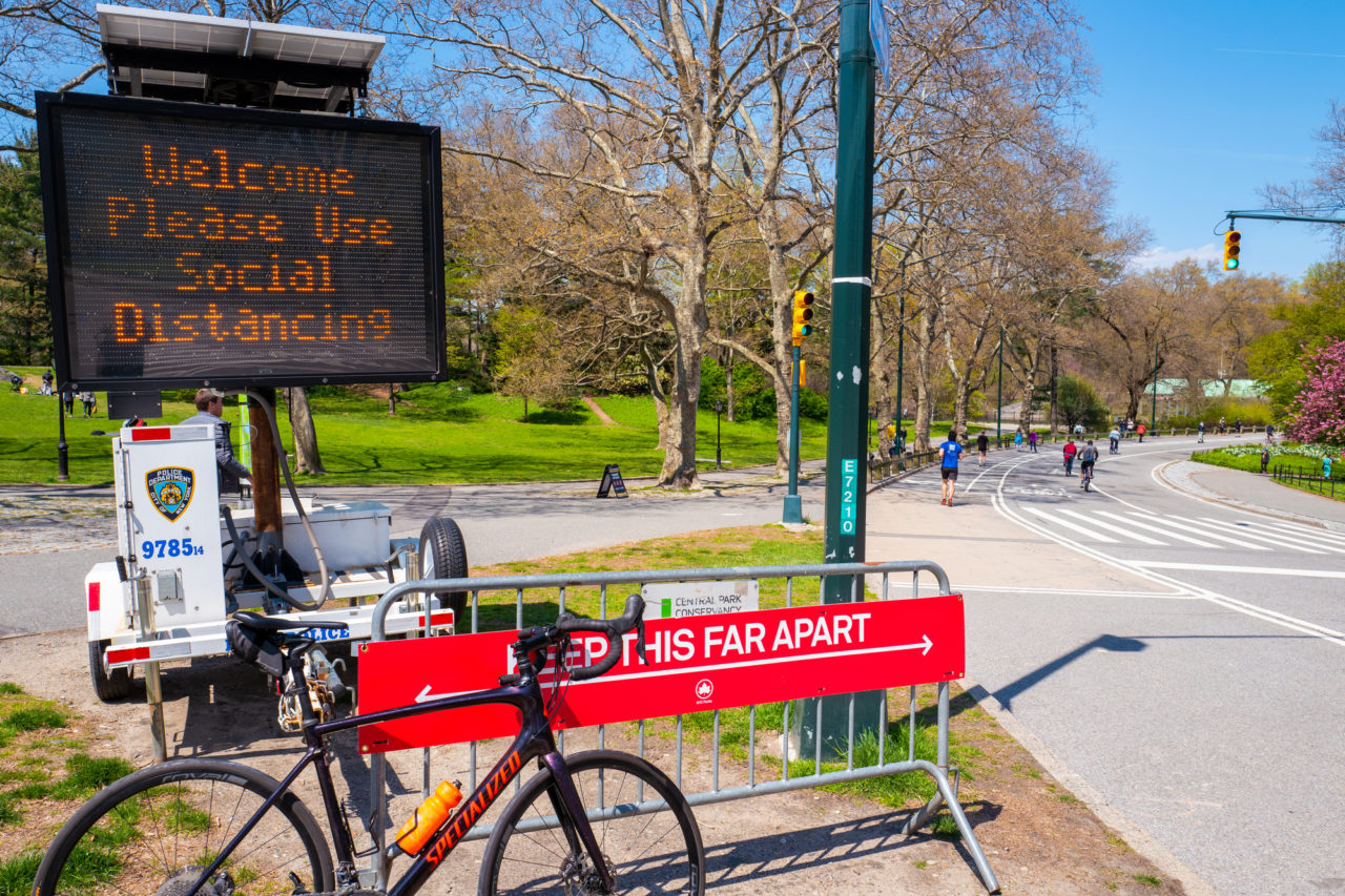 Central Park, New York, USA - April 19, 2020: New York City parks dept and NYPD display a sign demonstrating social distancing during the coronavirus pandemic lockdown in New York.