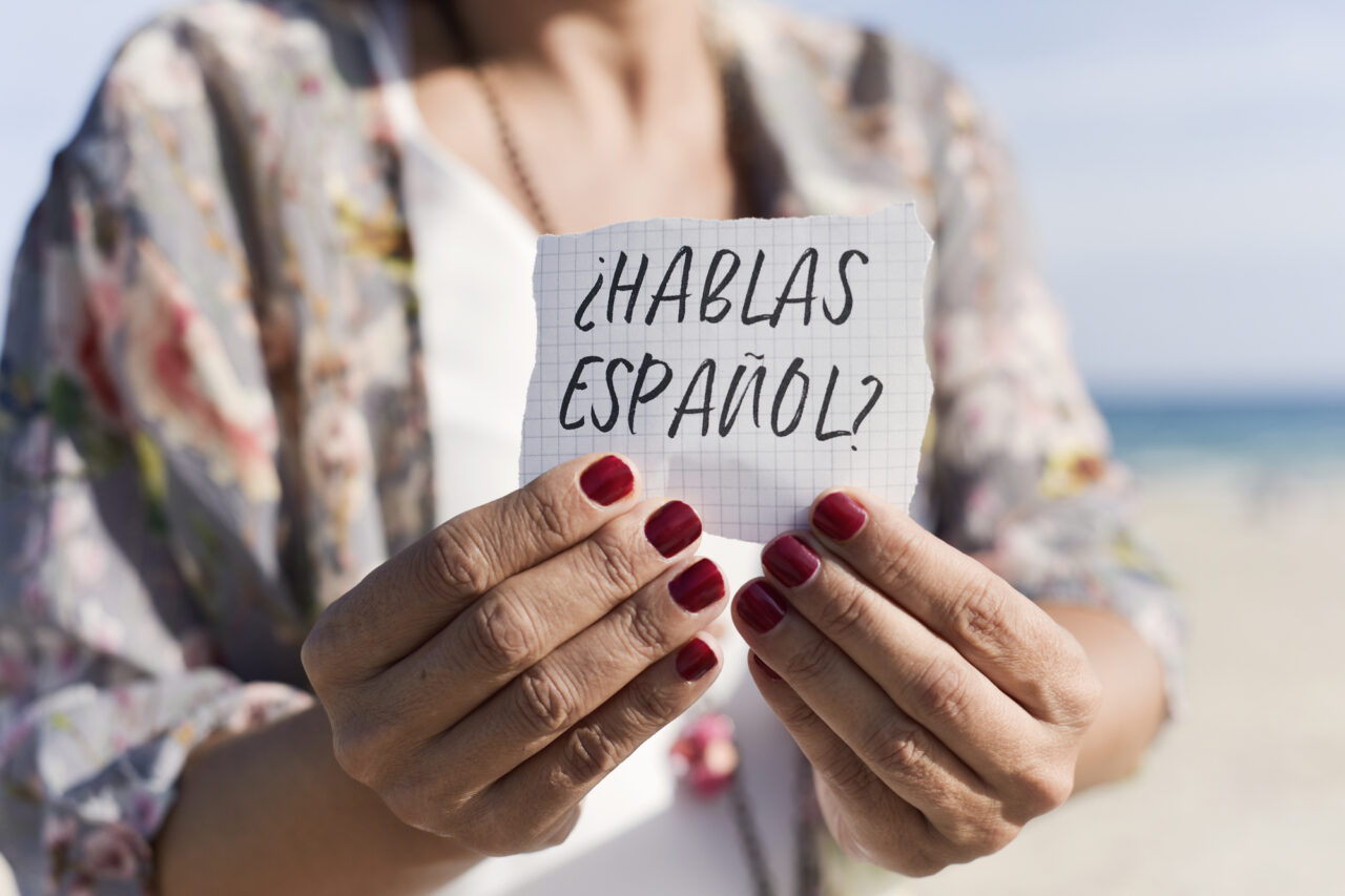pregunta ¿Hablas español? en una nota sostenida por una mujer