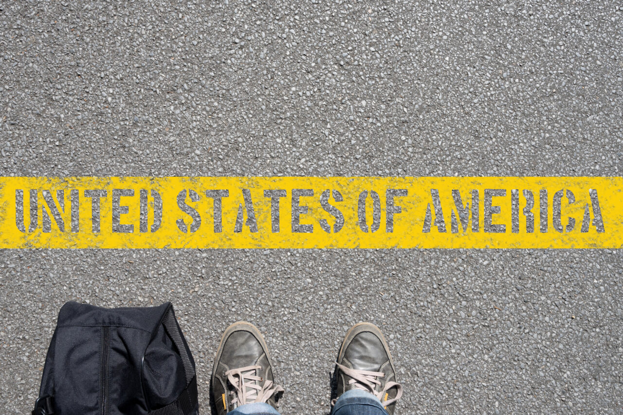 Par de pies y maleta en la linea fronteriza con Estados Unidos