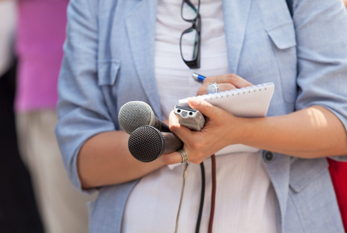 Periodista, conferencia de prensa, microfonos y grabadoras en las manos